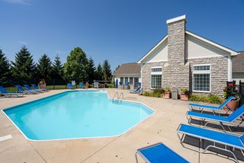 A pool with blue water and chairs around it.